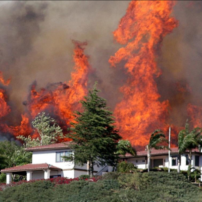 Jesusita fire burning behind a hillside house.
